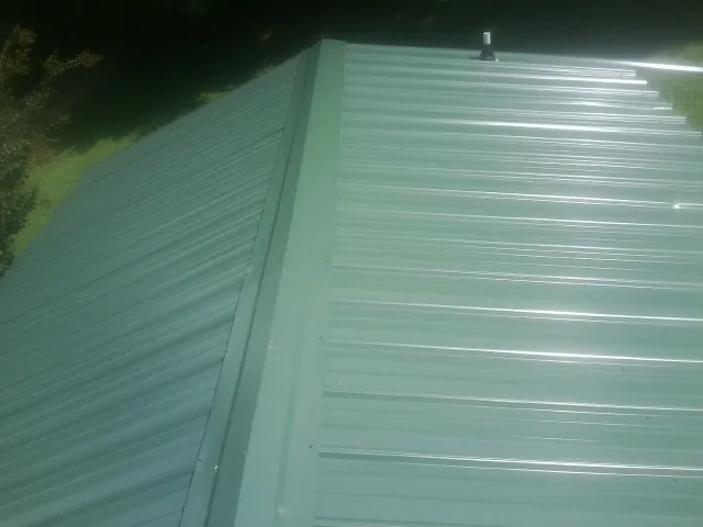 New green metal panels meeting at the ridge of a roof — Flat Roof Repair work by our crew in Anaconda