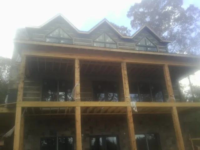 Dormers and porch framing on a large log home under construction — Roof Coating work by our crew in Anaconda