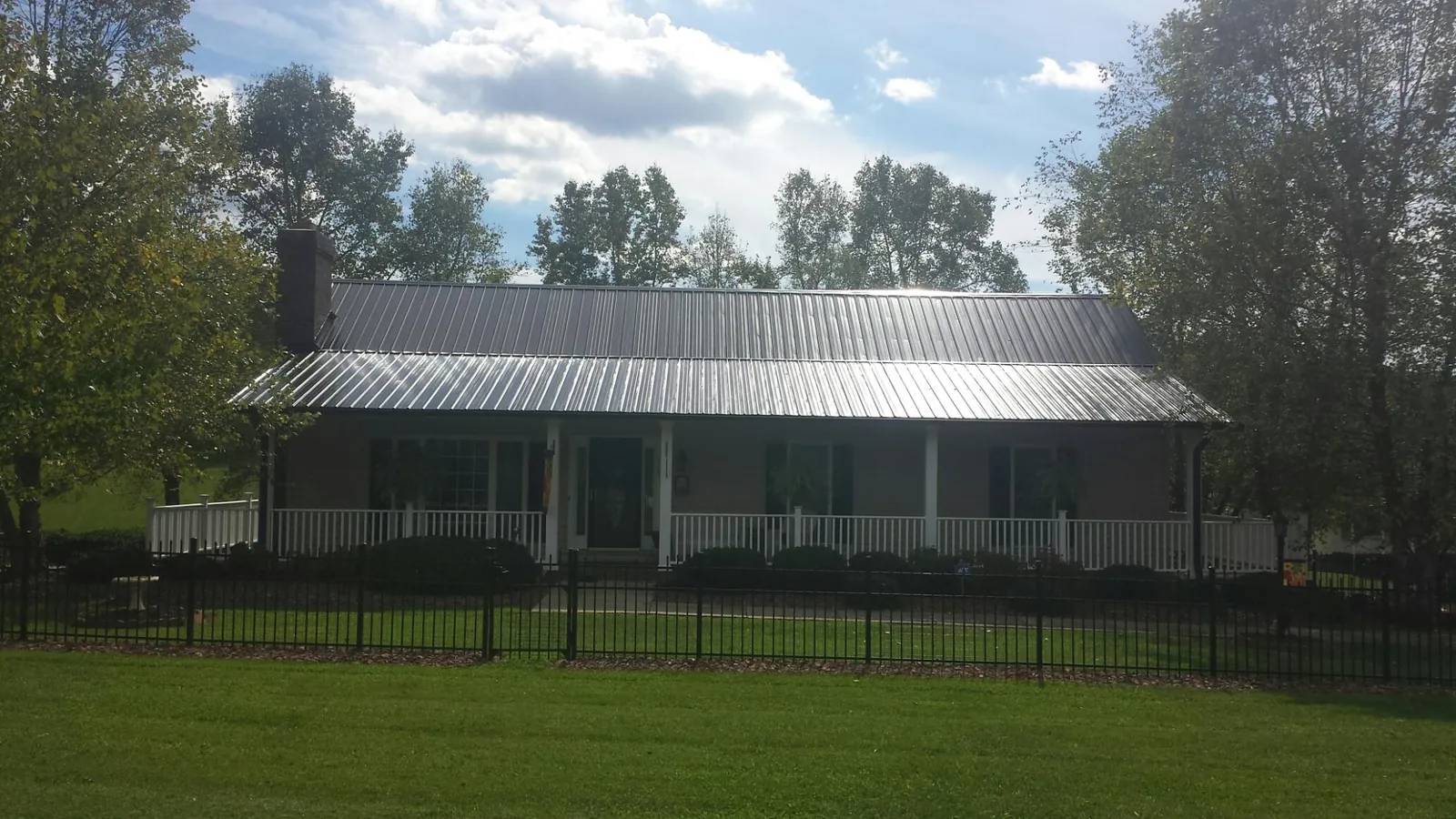 Gray metal roof on a brick ranch with a full width front porch — Gutter Guard Installation work by our crew in Anaconda