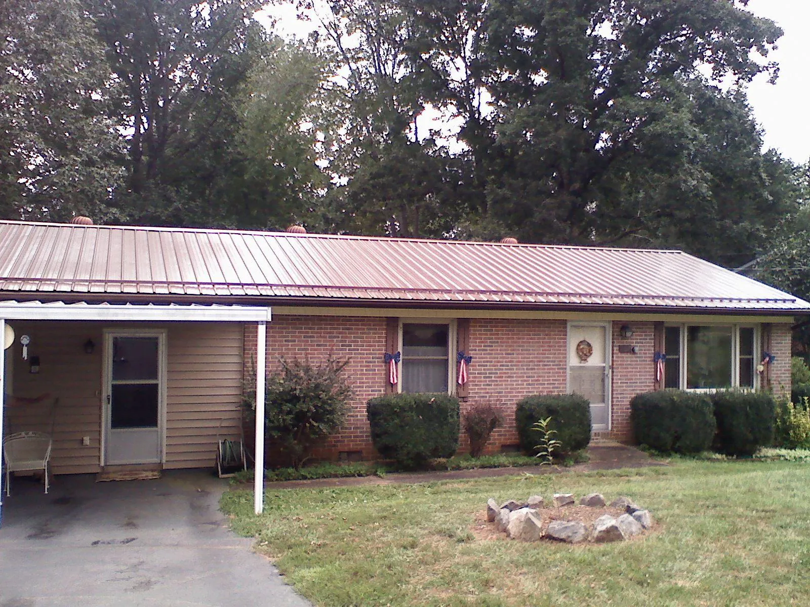 Bronze metal roof and carport on a brick ranch home — Roof Repair work by our crew in Anaconda