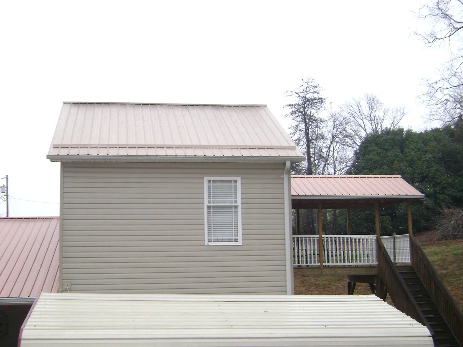 Tan metal roofs on a two story addition and attached porch, from a Roof Replacement job in Anaconda