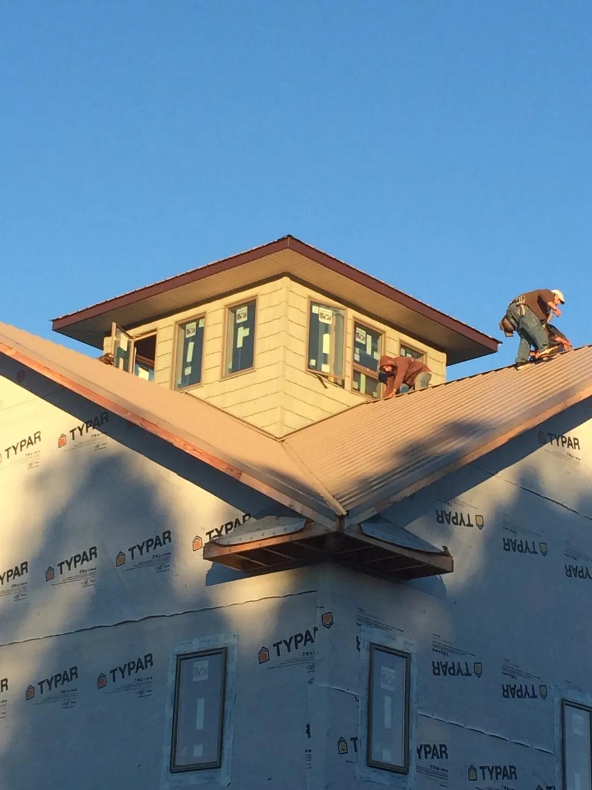 Roofers working around a rooftop cupola on a new metal roof at sunset — Roof Waterproofing in Anaconda by Roofing Brothers